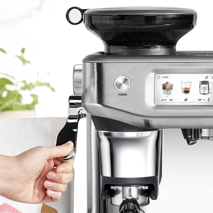 The automatic steam wand of the Breville Barista Touch Impress Stainless perfectly frothing milk in a stainless steel pitcher